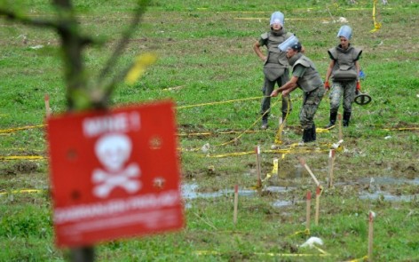 Bosnian soldiers repair land-mine warning signs in fields near the banks of the Bosnia River, which flooded near the town of Visoko, Bosnia-Herzegovina