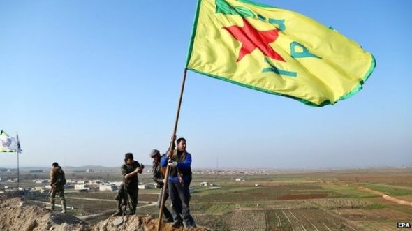 Kurdish fighters flew the flag of the Popular Protection Units on a hill overlooking Kobane on Monday