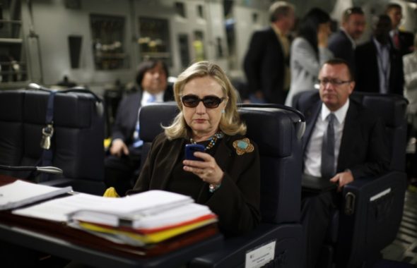 In this Oct. 18, 2011, file photo, then-Secretary of State Hillary Rodham Clinton checks her Blackberry from a desk inside a C-17 military plane upon her departure from Malta, in the Mediterranean Sea, bound for Tripoli, Libya. (AP)