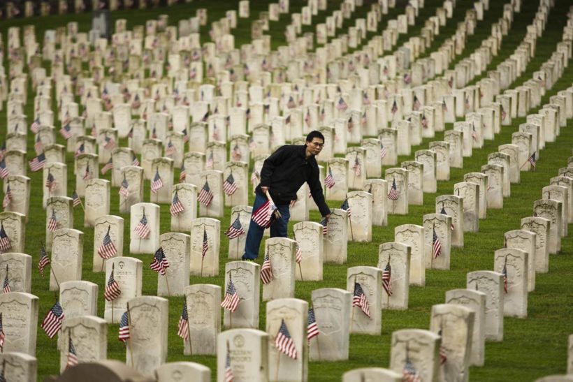 A man places a flag at a grave at Cypress Hills National Cemetery in Brooklyn, New York May 25, 2013. The annual "Flags-In" ceremony is held ahead of Memorial Day to honor the nation's fallen members of the military. Flags will be placed at more than 220,000 graves. REUTERS/Eduardo Munoz
