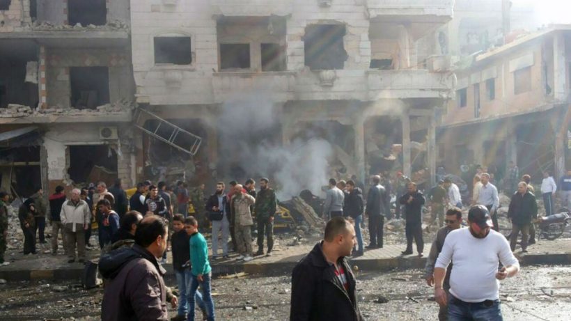 In this photo released by the Syrian official news agency SANA, residents gather at the scene where two blasts exploded in the pro-government neighborhood of Zahraa, in Homs province, Syria, Sunday, Feb. 21, 2016. (SANA via AP)